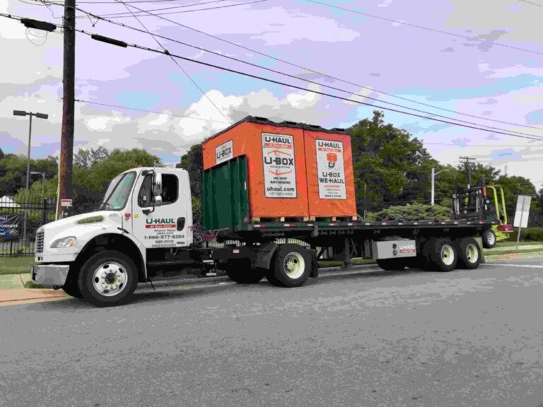 A truck driving with a load of two orange U-Box moving containers