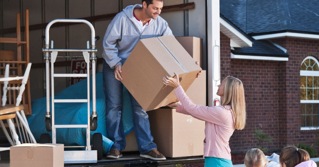 Family carrying and lifting moving boxes into a moving container