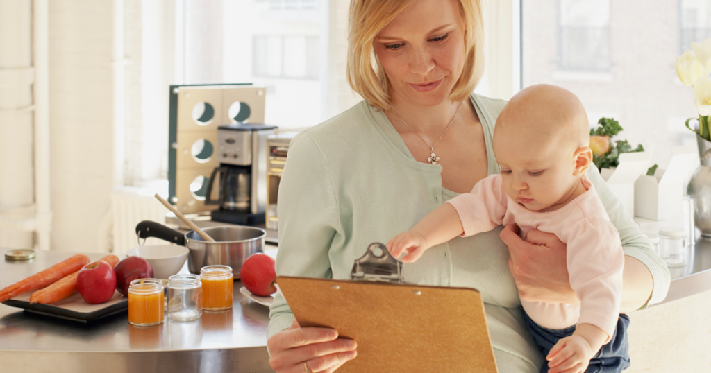 woman with a baby in her arms going over a clipboard checklist