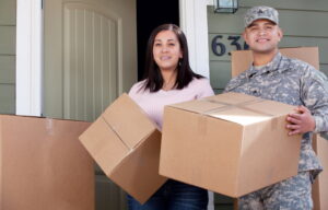 A military serviceman and spouse holding boxes for a personally procured move (PPM).