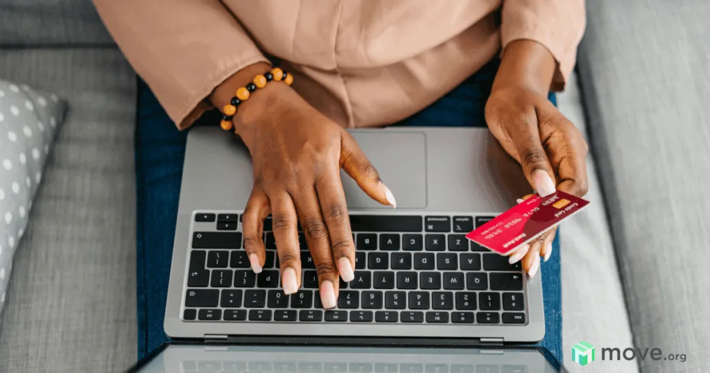 woman's hands typing on a laptop with a credit card in one hand