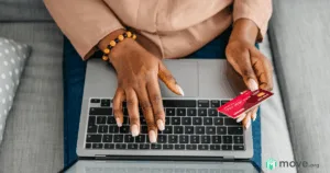 woman's hands typing on a laptop with a credit card in one hand