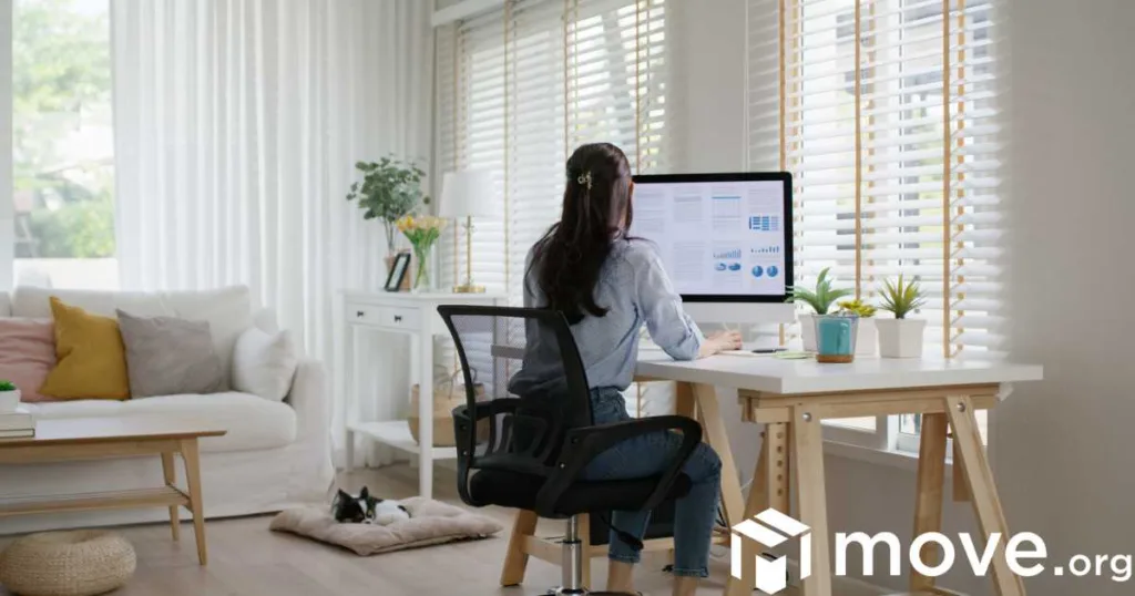 A woman sits facing her computer, working from home at a desk.