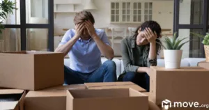Exhausted young couple sit on sofa in living room near heap of cardboard boxes after movers didn't show up.