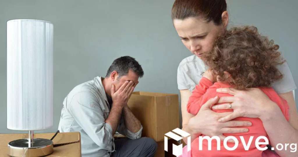 Mom comforting a child stressed out about moving, with dad in the background, and moving boxes.