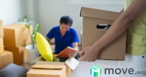 Arms holding a moving box in front of a man unpacking a box