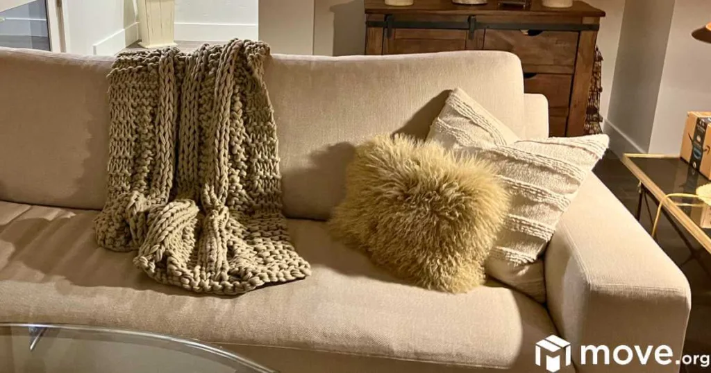 A cozy sofa with a fluffy throw and pillows, lighted softly for reading.