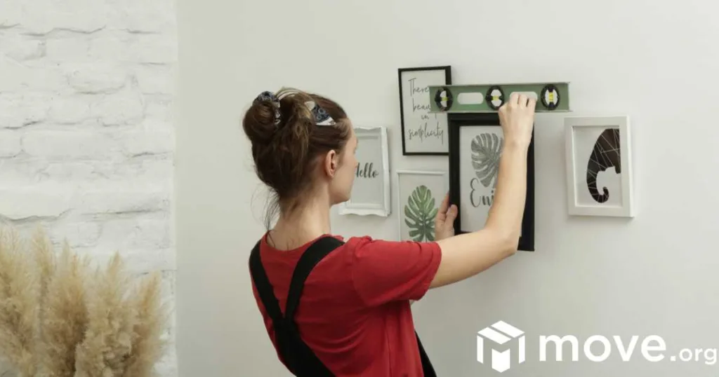 Woman using a level to hang a picture frame on a wall