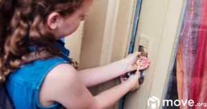 Young redhead girl getting home alone after school day. She is holding the house key to open the door.