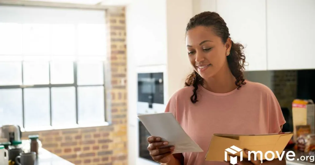 A woman reading a new address announcement from a friend, in the kitchen.
