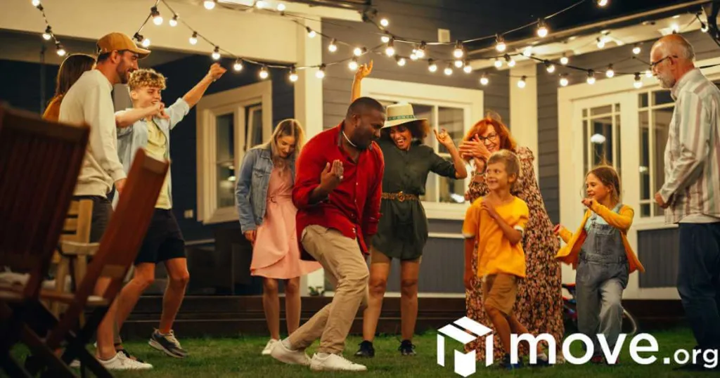 Group of multicultural diverse neighbors having fun and dancing together at an evening garden party.